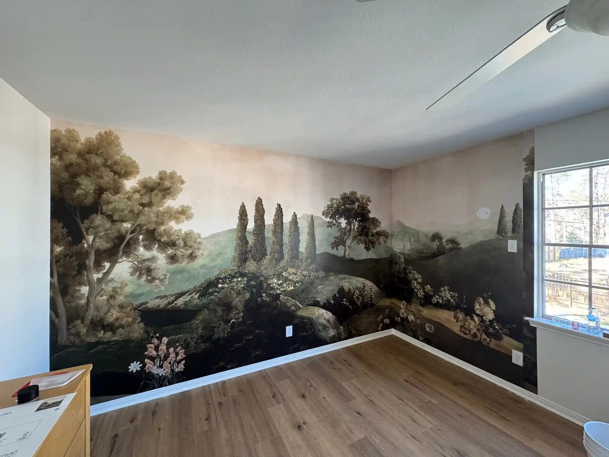A room with a detailed landscape mural wallpaper installation